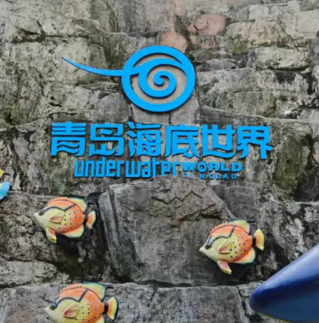 The Qingdao Underwater World logo carved on a rock face with corals